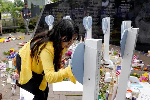 Yesenia Hernandez, granddaughter to Nicolas Toledo, who was killed during Monday's Highland Park., Ill., Fourth of July parade, writes on a memorial for Toledo along with the six others who lost their lives in the mass shooting, Wednesday, July 6, 2022, in Highland Park. (AP Photo/Charles Rex Arbogast)