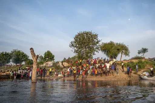 People gather along a flooded area in Jonglei state, South Sudan, Wednesday, Nov. 13, 2024. (AP Photo/Florence Miettaux)