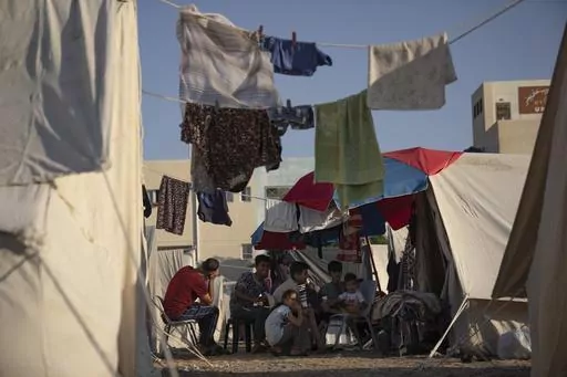 Palestinians displaced by the Israeli bombardment of the Gaza Strip siti in a UNDP-provided tent camp in Khan Younis, on Thursday, Oct. 19, 2023. Since the Israeli military decided to cut off the Gaza Strip's water and fuel and prevent aid convoys from entering, Palestinians in Gaza have sheltered with their families far from their homes and struggled to survive. It's a grueling routine — waiting hours for bread, trying to find water, soothing children during bombings. (AP Photo/Fatima Shbair)