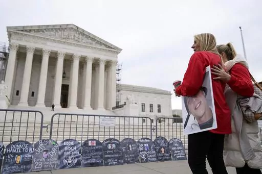 Jen Trejo holds a photo of her son Christopher as she is comforted outside the Supreme Court Monday, Dec. 4, 2023, in Washington. Her son was 32 when he died and she said about Purdue Pharma and the Sackler family, "You can't just kill my child and just pay a fine." The Supreme Court is wrestling with a nationwide settlement with OxyContin maker Purdue Pharma that would shield members of the Sackler family who own the company from civil lawsuits over the toll of opioids. (AP Photo/Stephanie Scar