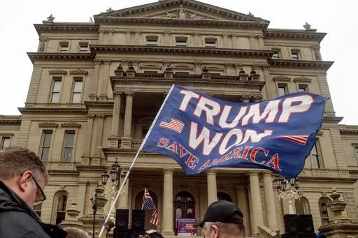 A protester waves a Trump flag during rally organized by a group called Election Integrity Fund and Force at the Michigan State Capitol, Tuesday, Oct. 12, 2021, in Lansing, Mich. Michigan Attorney General Dana Nessel has charged 16 Republicans Tuesday, July 18, 2023, with multiple felonies after they are alleged to have submitted false certificates stating they were the state’s presidential electors despite Joe Biden’s 154,000-vote victory in 2020. The group includes Republican National Comm