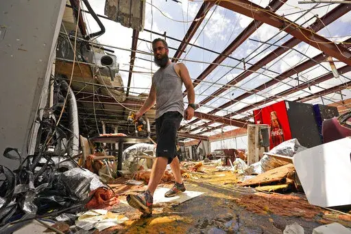 Jason Ledet relieves a tool as he works in a destroyed bowling alley as they try to recover from the effects of Hurricane Ida Tuesday, Aug. 31, 2021, in Houma, La. (AP Photo/Steve Helber)