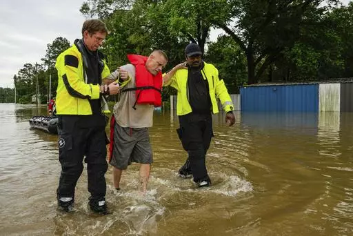 Tim McCanon, center, is rescued by the Community Fire Department during severe flooding on Friday, May 3, 2024, in New Caney, Texas. In a world growing increasingly accustomed to wild weather swings, the last few days and weeks have seemingly taken those environmental extremes to a new level. (Raquel Natalicchio/Houston Chronicle via AP, File)