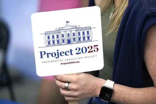 Kristen Eichamer holds a Project 2025 fan in the group's tent at the Iowa State Fair, Aug. 14, 2023, in Des Moines, Iowa. (AP Photo/Charlie Neibergall, File)