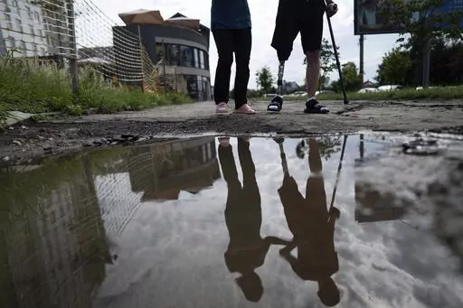 Roman Yarmolenko, a Ukrainian soldier from the 93rd brigade, learns to walk on a prosthetic leg. He crosses rough, muddy terrain outside the Unbroken rehabilitation center in Lviv, Ukraine, Wednesday, July 26, 2023. Ukraine is facing the prospect of a future with upwards of 20,000 amputees, many of them soldiers who are also suffering psychological trauma from their time at the front. (AP Photo/Evgeniy Maloletka)