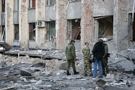 Investigators inspect a site after shelling near an administrative building, in Donetsk, the capital of Donetsk People's Republic, eastern Ukraine, Sunday, Oct. 16, 2022. According to the Donetsk People's Republic's (DPR) mission to the Joint Center for Control and Coordination, six 155mm munitions were fired at Donetsk in the early hours of Sunday. (AP Photo/Alexei Alexandrov)