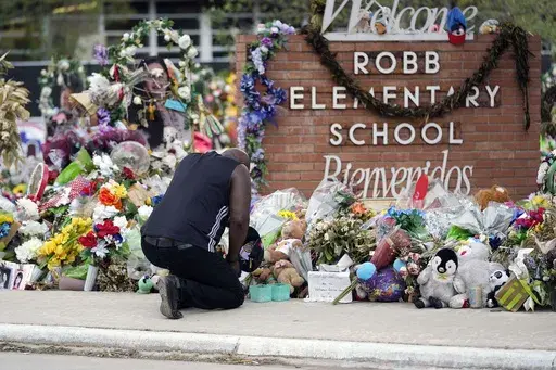 Reggie Daniels pays his respects a memorial at Robb Elementary School, June 9, 2022, in Uvalde, Texas, created to honor the victims killed in the school shooting. The former Uvalde schools police chief and another former officer have been indicted over their role in the slow police response to the 2022 massacre in a Texas elementary school that left 19 children and two teachers dead, according to multiple reports Thursday, June 27, 2024. (AP Photo/Eric Gay, File)