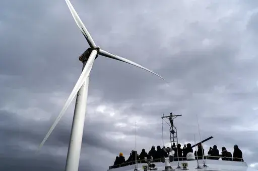 FILE Guests tour one of the turbines of America's first offshore wind farm, owned by the Danish company, Orsted, off the coast of Block Island, R.I., as part of a wind power conference, Oct. 17, 2022. A new AP-NORC poll shows that nearly two-thirds of Americans think the federal government is not doing enough to fight climate change, even as they have limited awareness about a sweeping new law that commits the U.S. to its largest ever investment to combat global warming. (AP Photo/David Goldman,