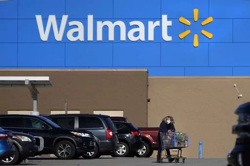 A woman wheels a cart with her purchases out of a Walmart store, Nov. 18, 2020, in Derry, N.H. Business closings on Christmas Eve are less common than those on Christmas Day, but many large chains still cut back hours or close up shop early for the coming holiday. Walmart will close at 6 p.m. on Christmas Eve, Sunday, Dec. 24, 2023. (AP Photo/Charles Krupa, File)