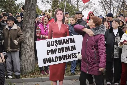 A woman slaps a cardboard cutout of Moldova's pro-western President Maia Sandu, with writing reading "Enemy of the Moldovan People", during a protest initiated by the populist Shor Party, in Chisinau, Moldova, Sunday, Nov. 13, 2022. Shor, a fugitive Moldovan oligarch and opposition leader has been sentenced in absentia to 15 years in jail for his alleged role in a one-billion-dollar bank fraud case, Moldova's President said. The Court of Appeal in the capital, Chisinau, sentenced Ilan Shor, who 