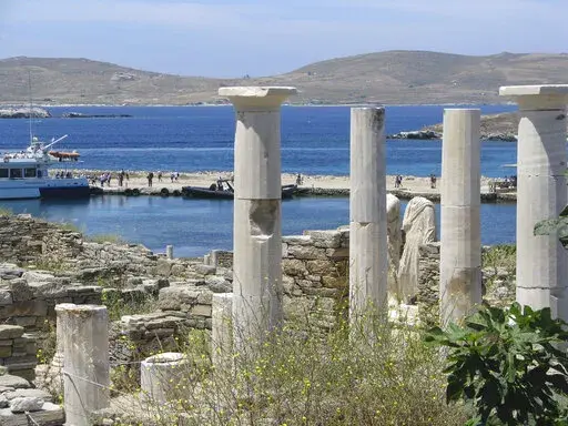 Ancient statues and columns from a millennia-old house stand just above the landing dock in the archaeological park at Delos, Greece, on May 25, 2019. The tiny island, a short boat ride from party-central Mykonos, was considered holy by ancient Greeks.  (AP Photo/Giovanna Dell’Orto)