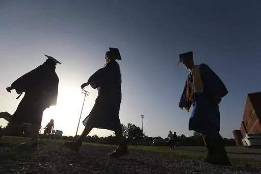 In this June 27, 2020, file photo, Saltillo High School seniors make their way to the football field as the sun begins to set for their graduation ceremony in Saltillo, Miss. Federal parent PLUS loans have become a last resort for many lower-income families paying for a kid’s college education. Today, parent PLUS loan debt totals $108.5 billion among 3.7 million borrowers, and the average borrower owes more than $29,000. (Thomas Wells/The Northeast Mississippi Daily Journal via AP, File)