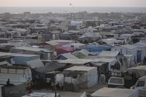 Palestinians displaced by the Israeli air and ground offensive on the Gaza Strip walk through a makeshift tent camp in Khan Younis, Gaza, Tuesday, June 18, 2024. (AP Photo/Jehad Alshrafi)