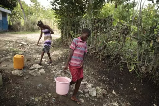 Siblings Mylouise Veillard, left, and Myson walk home with water they collected from a well, for cooking, cleaning and drinking, in a rural area of Saint-Louis-du-Sud, Haiti, Thursday, May 25, 2023. The siblings were considered “poverty orphans" for three years until they were reunited with their mother, Renèse Estève, who had dropped them off at an orphanage where she believed they'd get better care. Their mother brought them home after she was startled at the weight they had lost, convince