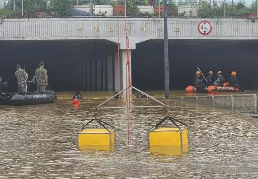 In this photo provided by South Korea National Fire Agency, rescuers search for survivors along a road submerged by floodwaters leading to an underground tunnel in Cheongju, South Korea, Sunday, July 16, 2023. Days of heavy rain triggered flash floods and landslides and destroyed homes, leaving scores of people dead and forcing thousands to evacuate, officials said Sunday.(South Korea National Fire Agency via AP)