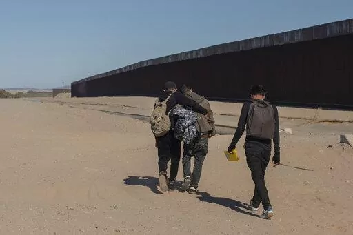 Nicaraguan migrants walk on the US-Mexico border, in Algodones, Baja California, Mexico, Dec. 2, 2021. The group walked into the U.S. and turned themselves over to the border patrol asking for asylum. The Biden administration has a draft plan to end sweeping asylum limits at the U.S.-Mexico border by May 23 that were put in place to prevent the spread of COVID-19, according to people familiar with the plans. (AP Photo/Felix Marquez, File)