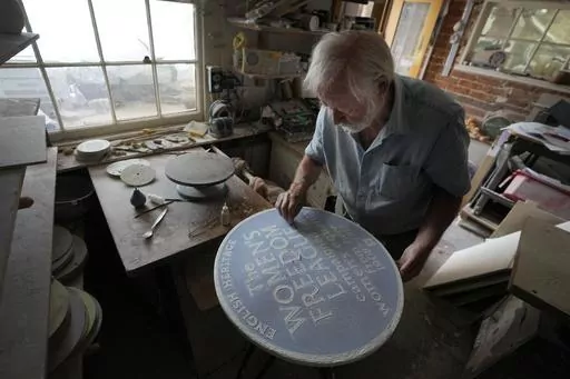 Ned Heywood fettling the glaze on the clay plaque during the making of an English Heritage Blue Plaque, at Heritage Ceramics, The Workshop Gallery in Chepstow, Wales Wednesday, Sept. 6, 2023. English Heritage is preparing to unveil its 1,000th blue plaque, the famous discs that dot the walls of buildings throughout London, marking the places where scientists, artists, politicians and activists have made history. The charity is working to broaden the program to include more women, people from min