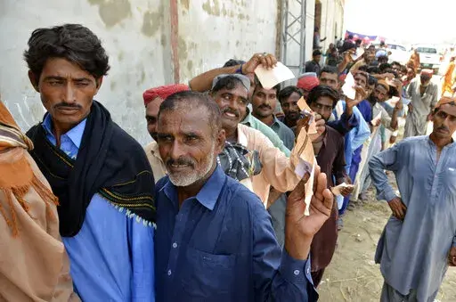 Displaced families, who fled their flood-hit homes, line up to get relief aid in Jaffarabad, a district of Baluchistan province, Pakistan, Wednesday, Sept. 21, 2022. Devastating floods in Pakistan's worst-hit province have killed 10 more people in the past day, including four children, officials said Wednesday as the U.N. children's agency renewed its appeal for $39 million to help the most vulnerable flood victims. (AP Photo/Zahid Hussain)