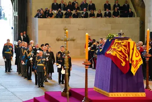 Photographers and reporters can be seen in background, upper right, with the coffin of Queen Elizabeth II on the catafalque in Westminster Hall, London, Wednesday Sept. 14, 2022. Plans by news organizations that have been in place for years — even decades — to cover the death of Queen Elizabeth II were triggered and tested when the event took place. London has been inundated with journalists, with more headed to the city for the funeral services on Monday. ( Jacob King/Pool via AP, File)