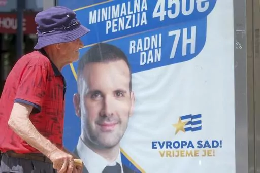 A man walks past a pre-election billboard showing leader of the Europe Now movement, financial expert Milojko Spajic in Podgorica, Montenegro, Friday, June 9, 2023. Montenegro is holding an early parliamentary election Sunday, a vote that could provide indications of whether the small NATO member in the Balkans will overcome the deep political divisions and instability that have hampered its route to joining the European Union. (AP Photo/Risto Bozovic)