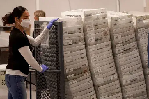 An election worker arrives with ballots to be tabulated inside the Maricopa County Recorders Office, Wednesday, Nov. 9, 2022, in Phoenix. (AP Photo/Matt York)