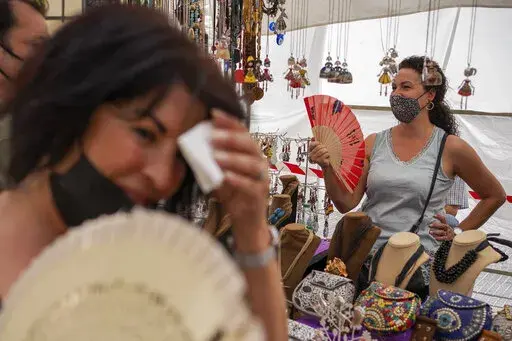 Women cool themselves with fans in the Rastro flea market during a heatwave in Madrid, Spain, Aug. 15, 2021. Scientists say last summer was the hottest summer on record in Europe, with temperatures a 1.8 Fahrenheit higher than the average for the previous three decades. A report released Friday, April 22, 2022 by the European Union’s Copernicus Climate Change Service found that while spring 2021 was cooler than average, the summer months were marked by “severe and long-lasting heatwaves.” 