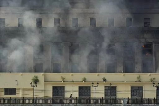 A man passes by the still smoldering Manila Central Post Office after it caught fire early Monday, May 22, 2023 in Manila, Philippines. On Friday, July 7, The Associated Press reported on stories circulating online incorrectly claiming a video shows a major library in France burning during riots sparked by the police killing of a 17-year-old. (AP Photo/Aaron Favila, File)