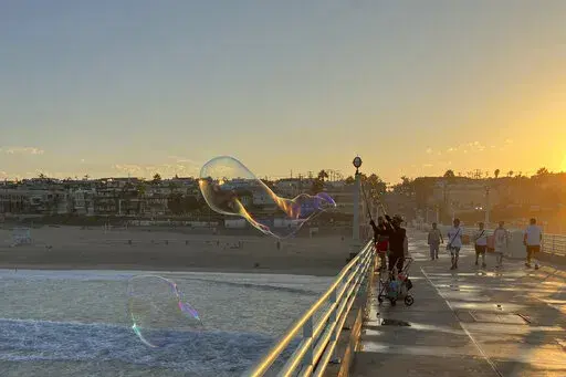 A man creates giant soap suds bubbles at dawn Monday, Sept. 5, on the Manhattan Beach Pier in Manhattan Beach, Calif., as a severe heat wave gripped the state. Most of California's 39 million people are facing sweltering weather. (AP Photo/John Antczak)