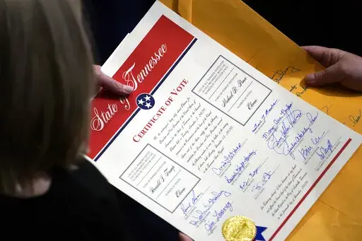 Staff members hold the certification of Electoral College votes from Tennessee during a joint session of the House and Senate to confirm Electoral College votes at the Capitol, early Jan 7, 2021, in Washington. Former President Donald Trump's relentless, false claims about the 2020 presidential election have sparked fresh urgency in Congress for changing the Electoral Count Act. (AP Photo/Andrew Harnik, File)