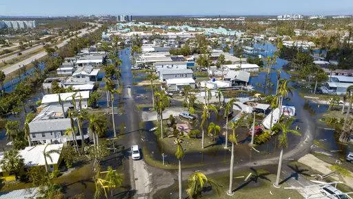 Water floods a damaged trailer park in Fort Myers, Fla., on Oct. 1, 2022, after Hurricane Ian passed by the area. Florida Gov. Ron DeSantis on Thursday, Oct. 13, 2022 announced an executive order expanding voting access for the midterm elections in three counties where Hurricane Ian destroyed polling places and displaced thousands of people. (AP Photo/Steve Helber, File)