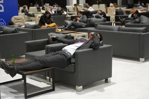 Attendees and members of the media lounge as they wait for a closing plenary session at the COP27 U.N. Climate Summit, Sunday, Nov. 20, 2022, in Sharm el-Sheikh, Egypt. (AP Photo/Peter Dejong)