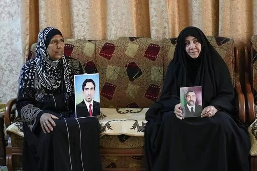 Nidal Ali, right, and Nawal Sweidan hold photos of their missing sons in Mahmoudiya, south of Baghdad, Iraq, Tuesday, March 28, 2023. Their sons were both kidnapped by extremist groups in 2014. Though active conflict in Iraq has largely subsided, many are still waiting to learn the fate of missing loved ones who disappeared during the US invasion, the subsequent civil war, or during the war against the Islamic State. (AP Photo/Hadi Mizban)