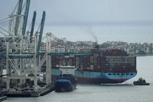 Tugboats guide the Axel Maersk container ship as it arrives into port, Oct. 21, 2021, in Miami. The marine shipping industry is facing new regulations to address carbon pollution. Its trade groups have been seeking exemptions for pollution emitted during voyages on rough seas. (AP Photo/Rebecca Blackwell, File)