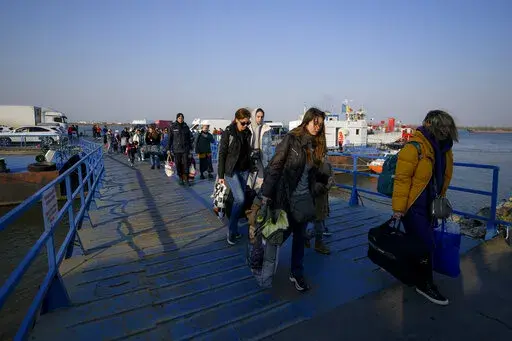 Refugees fleeing the war from neighbouring Ukraine walk after crossing the border by ferry at the Isaccea-Orlivka border crossing in Romania, Thursday, March 24, 2022. (AP Photo/Andreea Alexandru)