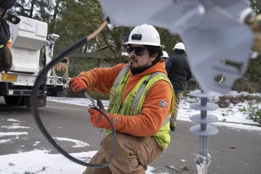 A worker from Portland General Electric replaces a power line as crews work to restore power after a storm on Jan. 16, 2024, in Lake Oswego, Ore. On Friday, Feb. 2, 2024, the U.S. government issues its January jobs report. (AP Photo/Jenny Kane, File)