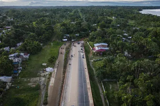 Vendors and moto-taxi drivers gather near an unfinished portion of a federal highway project on the Nanay bridge in Iquitos, Peru, Sunday, May 26, 2024. The project in an untouched area of the Peruvian Amazon is facing mounting opposition from Indigenous tribes, fearing that the construction will lead to land grabbing, deforestation and drug trafficking. (AP Photo/Rodrigo Abd)