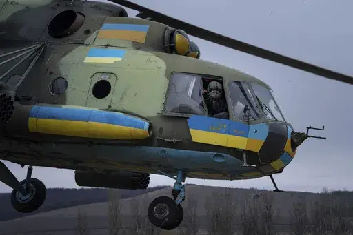 A Ukrainian pilot waves to his comrades from an Mi-8 combat helicopter during a combat mission in Donetsk region, Ukraine, Saturday, March 18, 2023. (AP Photo/Evgeniy Maloletka)