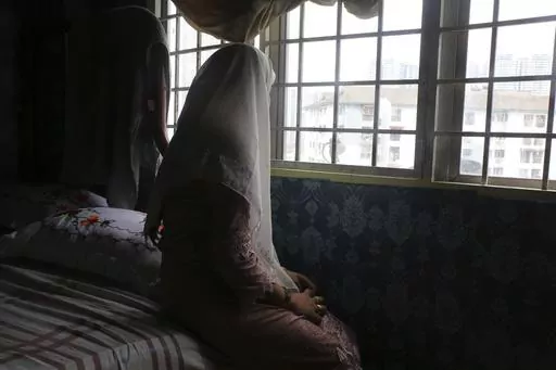 Rohingya child bride, B, age 14, sits on a bed in an apartment in Kuala Lumpur, Malaysia, on Oct. 4, 2023. B came to Malaysia in 2023 to marry an older man. Her husband wants her to get pregnant, but she says she doesn't feel ready. "I still feel like a girl." Deteriorating conditions in Myanmar and in neighboring Bangladesh’s refugee camps are driving scores of underage Rohingya girls to Malaysia for arranged marriages with Rohingya men who frequently abuse them, The Associated Press found in
