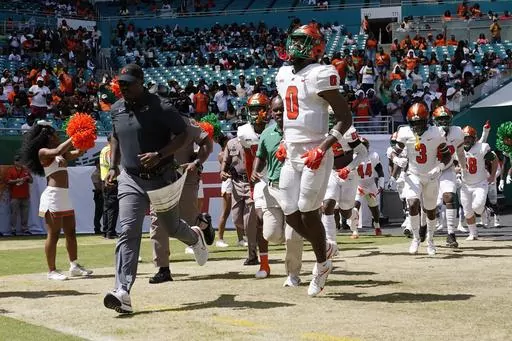 Florida A&M head coach Willie Simmons, left, runs onto the field before the Orange Blossom Classic NCAA college football game against Jackson State, Sunday, Sept. 4, 2022, in Miami Gardens, Fla. Florida A&M has banned its players from the team's facilities after a rap video featuring some Rattlers was shot in their locker room without proper permission being granted. Coach Willie Simmons told The Associated Press on Saturday, July 22, 2023, the team facility, weight room and access to the stadiu