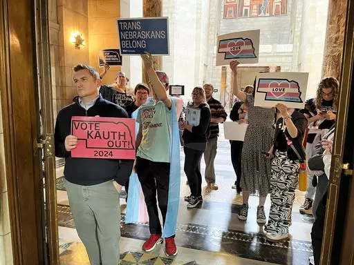 Protesters hold signs outside the doors of the legislative chamber in the Nebraska Capitol in response to a bill that would have restricted students to bathrooms, locker rooms and sports teams that correspond with the gender they were assigned at birth, April 5, 2024, in Lincoln, Neb. In a lawsuit filed Monday, April 29, four Republican state attorneys general are challenging a federal regulation that seeks to protect the rights of transgender students in the nation's schools by banning blanket 