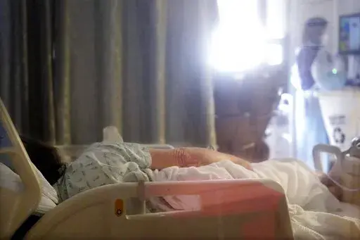 A COVID-19 patient lies in a bed in the acute care unit of Harborview Medical Center, Friday, Jan. 14, 2022, in Seattle. The U.S. came the closest to health care for all for the first time during the coronavirus pandemic. It was for just one condition, COVID 19. Now, things are reverting to the way they were as federal money for the uninsured dries up. Lack of an insurance card could become a barrier to timely care for COVID. (AP Photo/Elaine Thompson, File)