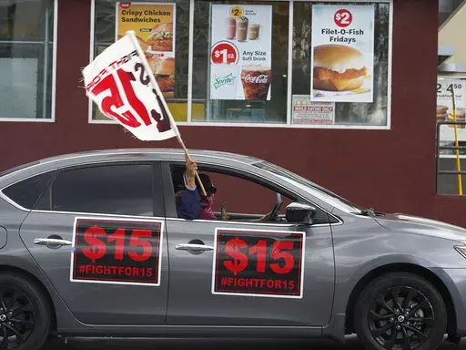 FILE - Fast-food workers drive though a McDonald's restaurant demanding a for a $15 hourly minimum wage in East Los Angeles Friday, March 12, 2021. Minimum wage increases, animal protections, police accountability, cutting and increasing taxes are all part of a series of new laws taking effect across the country on Saturday, the first day of 2022. (AP Photo/Damian Dovarganes, File)