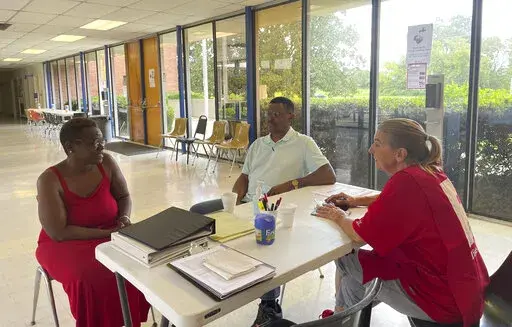 Veronique Daniels, left, speaks to Red Cross volunteers at a temporary shelter for people displaced by central Mississippi flooding, in Jackson, Miss, Sunday, Aug. 28, 2022. Daniels has been homeless for three months and three weeks. She had been sleeping on her mother's back porch when residents in the neighborhood were advised to evacuate. (AP Photo/Michael Goldberg)
