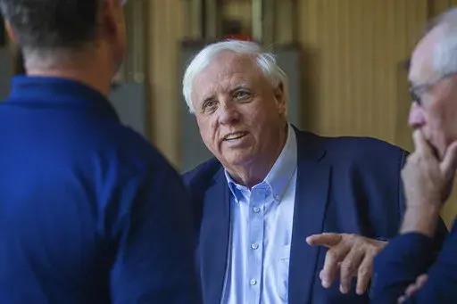 Gov. Jim Justice, center, speaks to Merl Wooten, owner of Wooten Machine Co., left, and Dr. Matthew Rohrbach while visiting community members on May 9, 2022, in Huntington, W.Va. Justice said Wednesday, Jan. 4, 2023, that he will announce a plan to cut taxes during his State of the State address on Jan. 11. (Ryan Fischer/The Herald-Dispatch via AP, File)