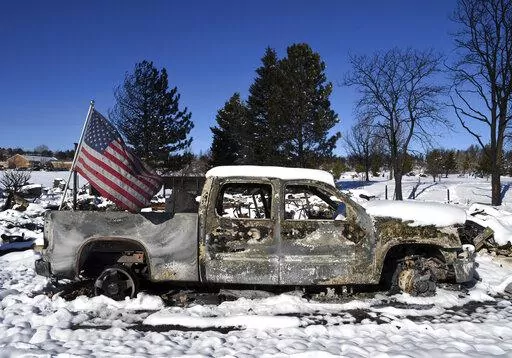 A burned truck in a destroyed neighborhood in Louisville, Colo., on Sunday, Jan. 2, 2022. Search teams looked for two missing people on Sunday in the snow-covered but still smoldering debris from a massive Colorado wildfire, while people who barely escaped the flames sorted through what was left after the blaze and investigators tried to determine its cause. (AP Photo/Thomas Peipert)