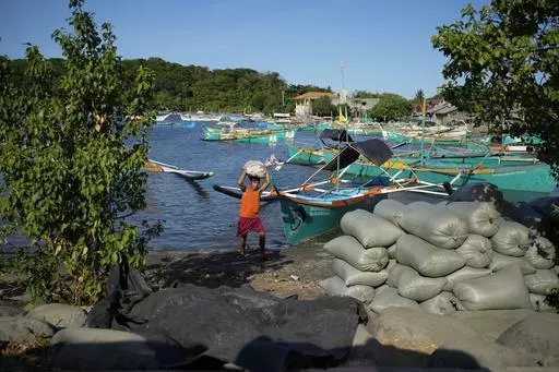 A resident brings down a sack from his boat at the coastal town of Santa Ana, Cagayan province, northern Philippines on Tuesday, May 7, 2024. The United States and the Philippines, which are longtime treaty allies, have identified the far-flung coastal town of Santa Ana in the northeastern tip of the Philippine mainland as one of nine mostly rural areas where rotating batches of American forces could encamp indefinitely and store their weapons and equipment within local military bases under the 