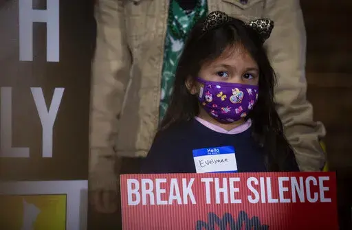 A child holds a sign at the beginning of a rally on Wednesday, March 16, 2022, in Atlanta. The Atlanta Asian Justice Rally was held on the anniversary of violence that left eight people shot and killed at various massage businesses on March 16, 2021, in the Atlanta area. Many family members and friends of the victims have been struggling with grief, trying to heal and making sure their loved ones aren't forgotten. (AP Photo/Ron Harris)