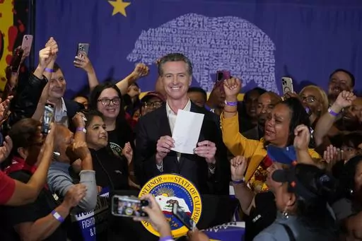 California Gov. Gavin Newsom signs the fast food bill surrounded by fast food workers at the SEIU Local 721 in Los Angeles, on Thursday, Sept. 28, 2023. Republican leaders in California are calling for an investigation into why a new state law requiring a $20 minimum wage for fast food workers includes an exemption for restaurants like Panera Bread. (AP Photo/Damian Dovarganes, File)
