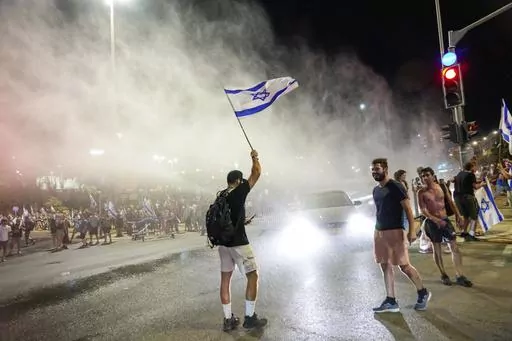 Israeli police use a water cannon to disperse demonstrators blocking a road during a protest against plans by Prime Minister Benjamin Netanyahu's government to overhaul the judicial system, in Jerusalem, Sunday, July 23, 2023. The demonstration came a day before parliament is expected to vote on a key part of the plan. (AP Photo/Ohad Zwigenberg)