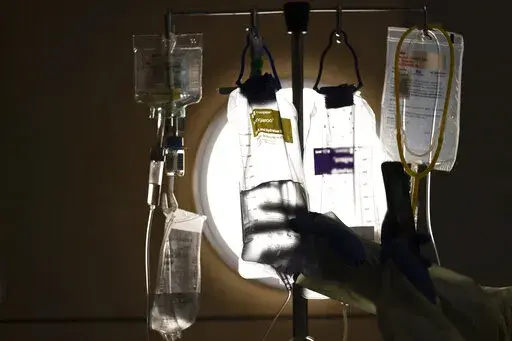 A nurse checks on IV fluids while talking to a COVID-19 patient at Providence Holy Cross Medical Center in Los Angeles, Dec. 13, 2021. When the end of the COVID pandemic comes, it could create major disruptions for U.S. health care. (AP Photo/Jae C. Hong, File)